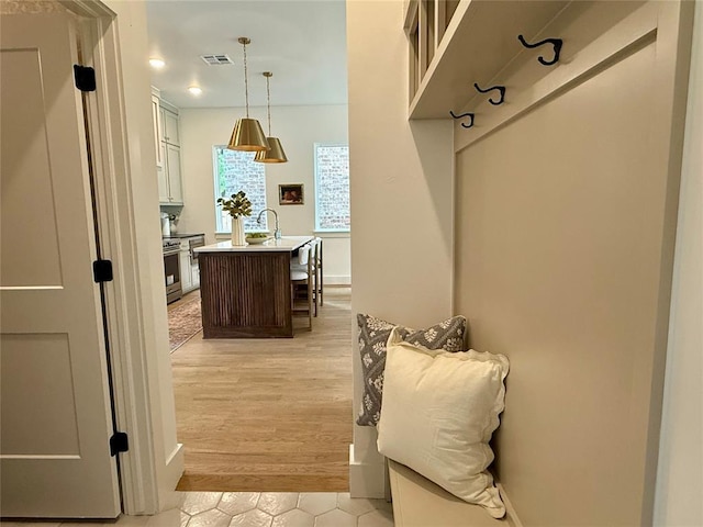 mudroom featuring light wood-style flooring, visible vents, and a sink