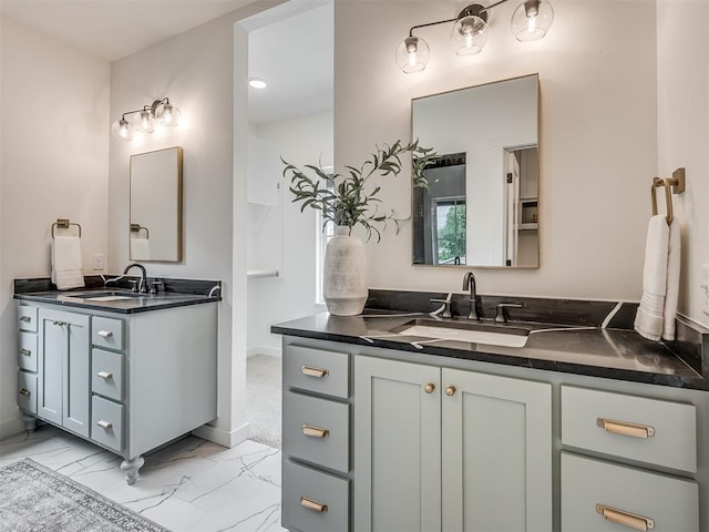 bathroom featuring a sink, two vanities, baseboards, and marble finish floor