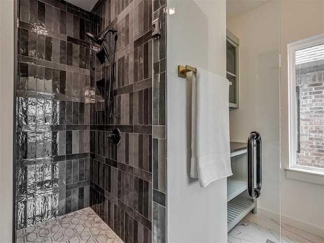 full bath with baseboards, marble finish floor, and a tile shower