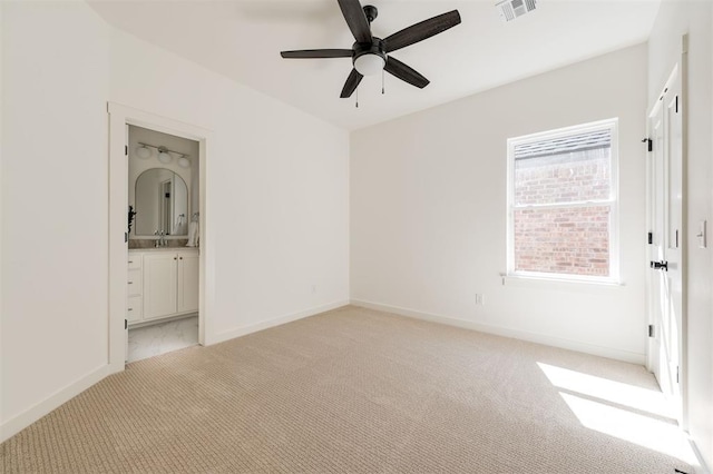 unfurnished bedroom with a sink, light colored carpet, visible vents, connected bathroom, and baseboards