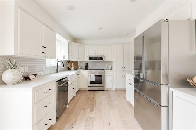 10912 Willow Grove Rd, Oklahoma City, OK 73120 - kitchen featuring decorative backsplash, white cabinets, a sink, light wood-style floors, and stainless steel appliances