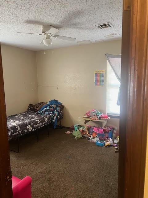 4912 Cinderella Dr, Oklahoma City, OK 73129 - carpeted bedroom with visible vents, a textured ceiling, and ceiling fan