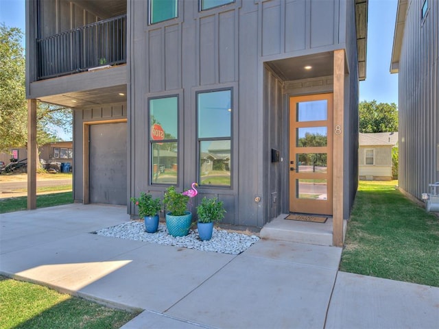 8 S Howard St, Edmond, OK 73003 - doorway to property with a balcony, a lawn, board and batten siding, and driveway