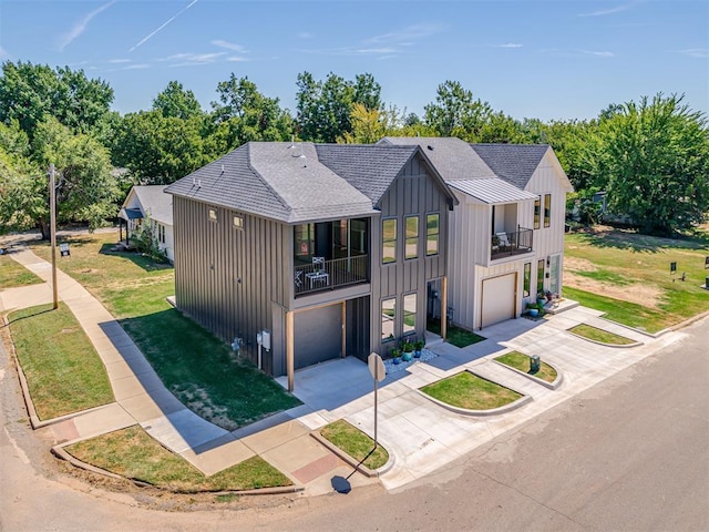 8 S Howard St, Edmond, OK 73003 - view of front facade with board and batten siding, concrete driveway, a front yard, an attached garage, and a balcony