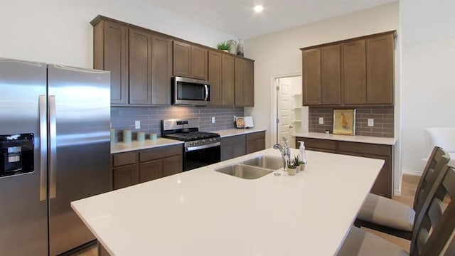 5412 Windstone Ln, Norman, OK 73072 - kitchen featuring stainless steel appliances, decorative backsplash, a kitchen island with sink, and light countertops