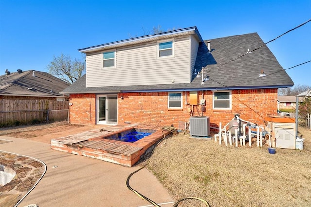 back of house featuring brick siding, fence, roof with shingles, and cooling unit