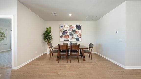 dining area featuring visible vents, baseboards, and light wood finished floors