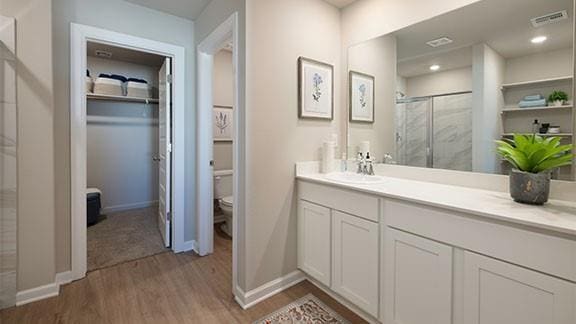 full bath featuring visible vents, a shower stall, toilet, wood finished floors, and vanity