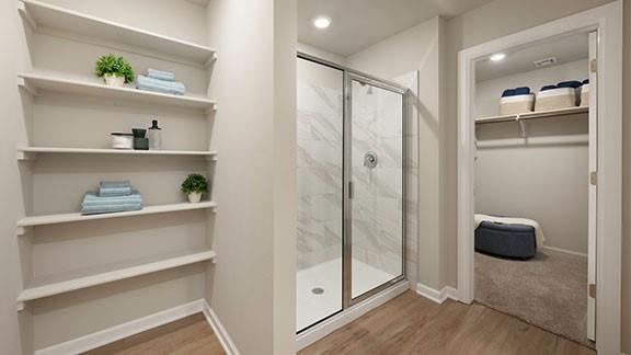 full bathroom featuring wood finished floors, baseboards, and a marble finish shower