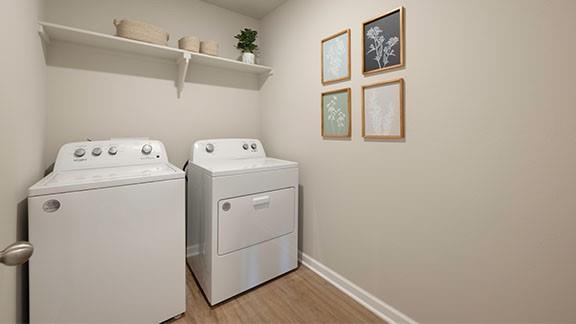 clothes washing area featuring washer and clothes dryer, laundry area, baseboards, and light wood-style floors