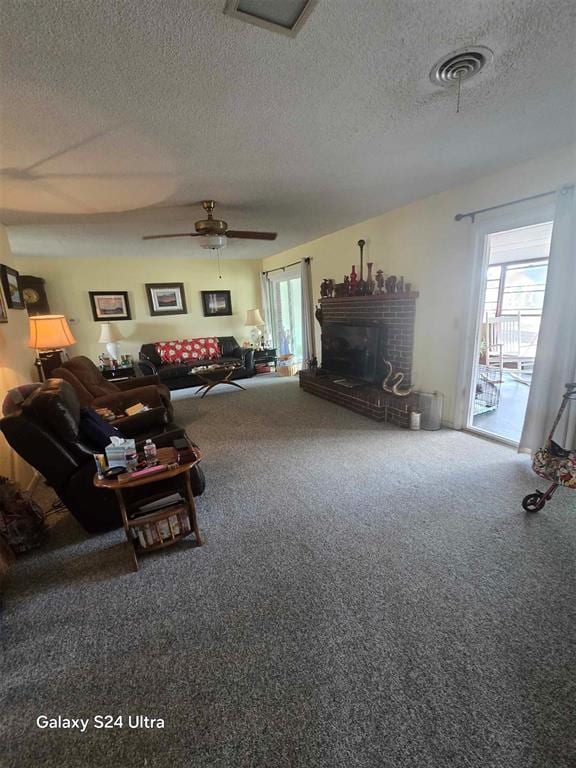 506 E Oklahoma St, Walters, OK 73572 - carpeted living room with visible vents, a textured ceiling, ceiling fan, and a fireplace