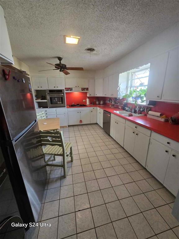 506 E Oklahoma St, Walters, OK 73572 - kitchen with a sink, white cabinets, stainless steel appliances, and a textured ceiling