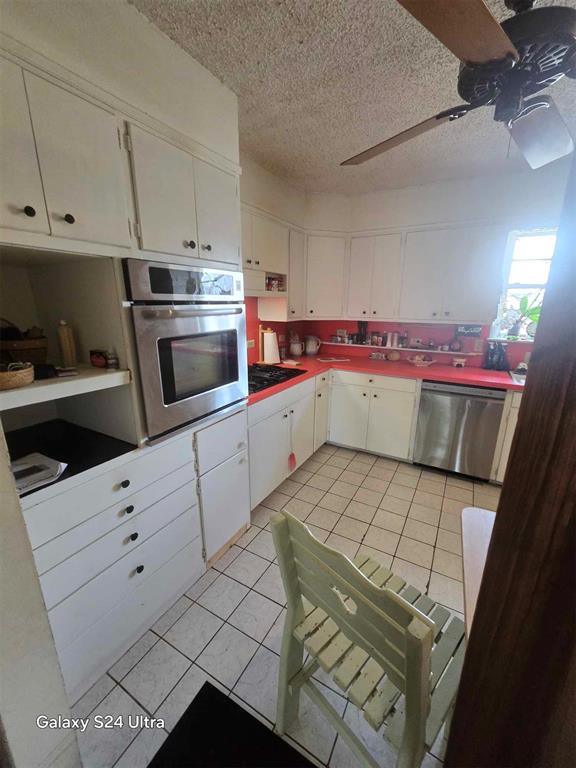506 E Oklahoma St, Walters, OK 73572 - kitchen featuring ceiling fan, a textured ceiling, white cabinetry, appliances with stainless steel finishes, and light tile patterned floors