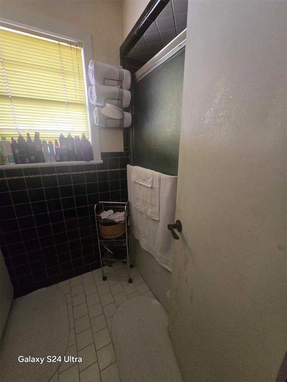 506 E Oklahoma St, Walters, OK 73572 - bathroom with tile patterned flooring and tile walls