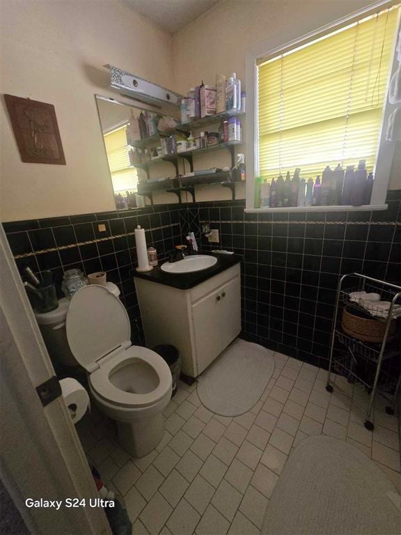 506 E Oklahoma St, Walters, OK 73572 - bathroom with wainscoting, vanity, toilet, tile patterned floors, and tile walls