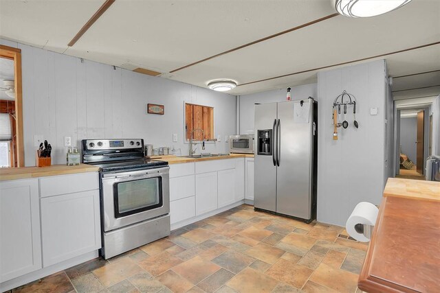 9872 N 2121st Pl, Butler, OK 73625 - kitchen featuring stainless steel appliances, a sink, wood counters, light stone finish floors, and white cabinetry