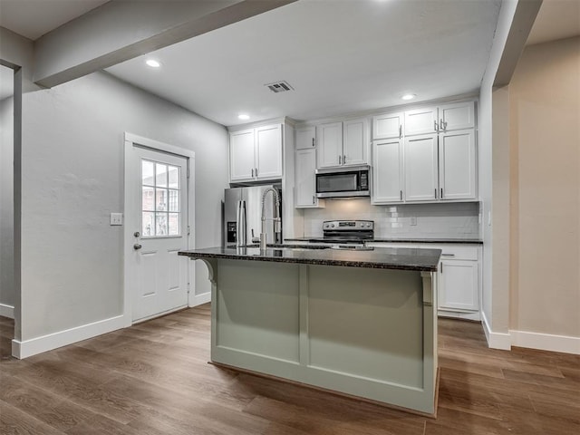 1604 NE Euclid St, Oklahoma City, OK 73117 - kitchen with dark wood-style floors, a center island with sink, visible vents, appliances with stainless steel finishes, and backsplash