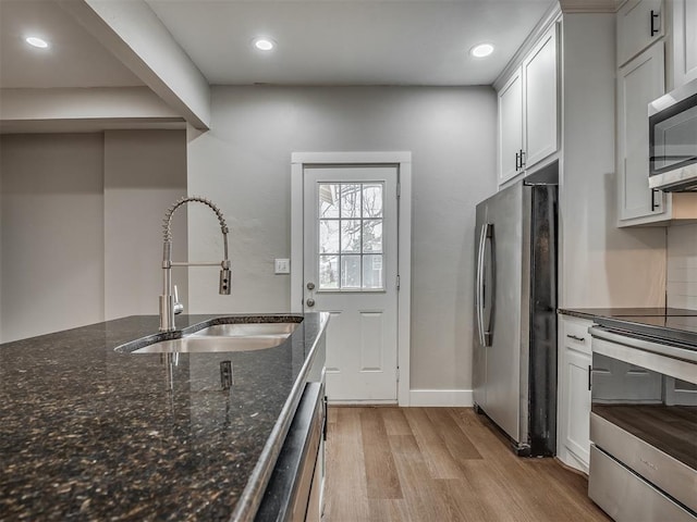 1604 NE Euclid St, Oklahoma City, OK 73117 - kitchen with a sink, dark stone countertops, white cabinetry, stainless steel appliances, and light wood finished floors
