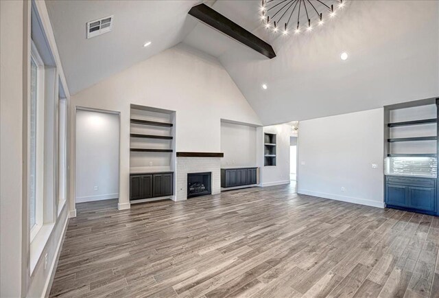 4201 Emery Dr, Edmond, OK 73034 - unfurnished living room featuring built in shelves, a chandelier, high vaulted ceiling, baseboards, and light wood-type flooring