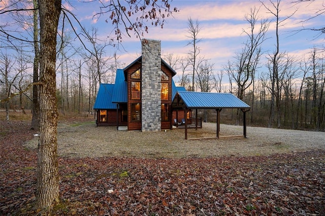 property exterior at dusk with faux log siding, a chimney, and metal roof