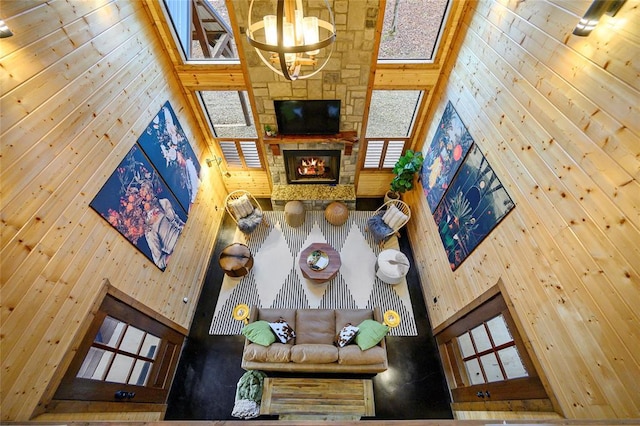living room with a towering ceiling, wooden walls, plenty of natural light, and a chandelier