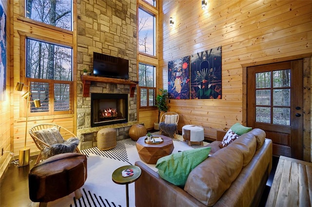 living room featuring a high ceiling, wood walls, a fireplace, and hardwood / wood-style flooring