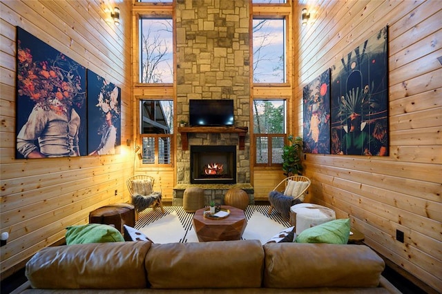 living area with wood walls, a fireplace, and a towering ceiling