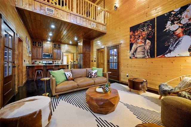 living area featuring wooden walls and a towering ceiling