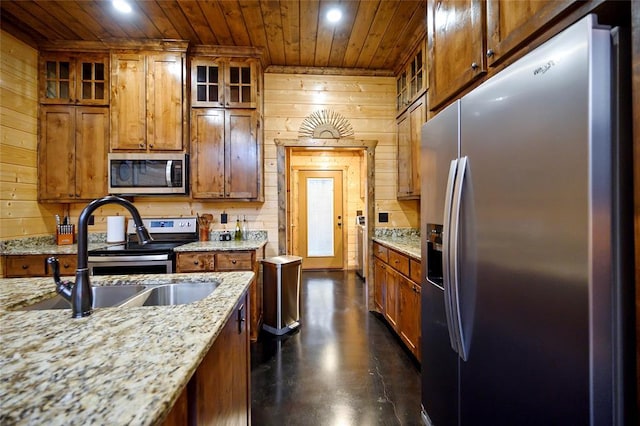 kitchen featuring stainless steel appliances, wood ceiling, wooden walls, a sink, and recessed lighting