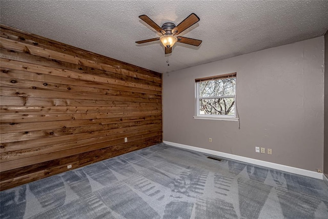 10900 Willow Grove Rd, Oklahoma City, OK 73120 - carpeted spare room featuring wood walls, ceiling fan, a textured ceiling, and baseboards