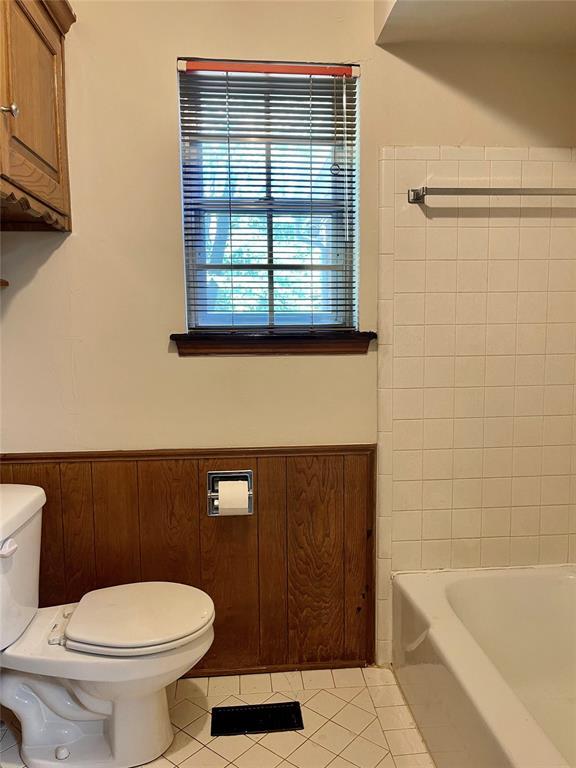 10900 Willow Grove Rd, Oklahoma City, OK 73120 - bathroom with toilet, tile patterned flooring, a tub to relax in, and a wainscoted wall