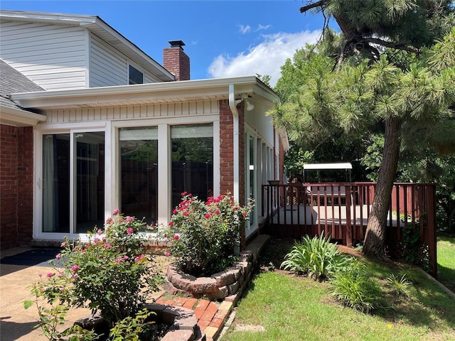 10900 Willow Grove Rd, Oklahoma City, OK 73120 - view of home's exterior featuring a wooden deck, a chimney, and brick siding