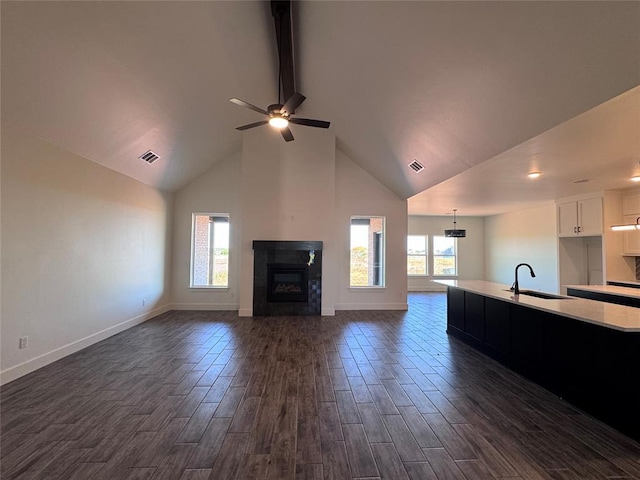 unfurnished living room featuring a sink, high vaulted ceiling, a glass covered fireplace, a ceiling fan, and visible vents