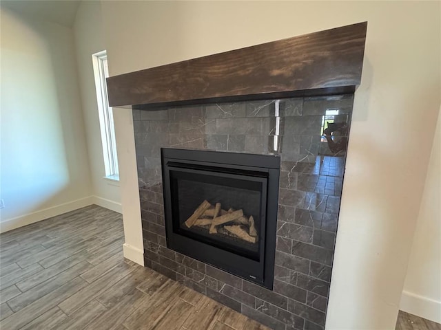 interior details featuring baseboards, a glass covered fireplace, and wood finished floors