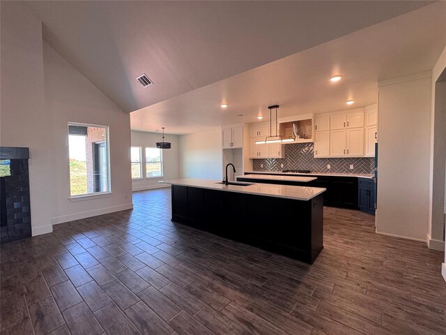 kitchen with baseboards, a sink, white cabinets, and visible vents
