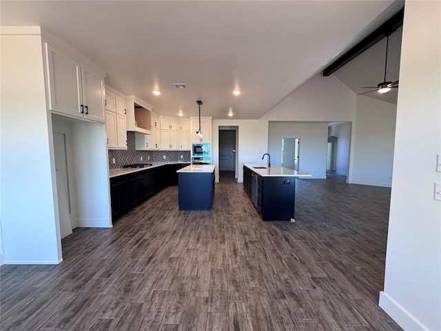 kitchen with a sink, an island with sink, stainless steel appliances, baseboards, and open floor plan