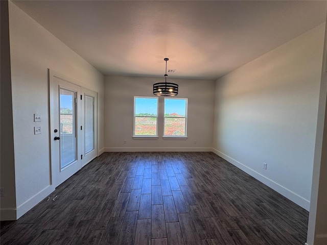 unfurnished dining area featuring dark wood-type flooring, baseboards, and a notable chandelier