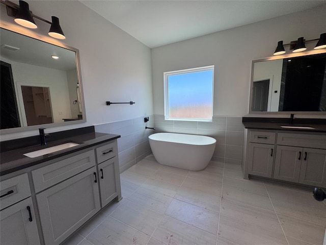 bathroom with a sink, tile walls, and two vanities
