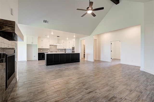9321 NW 147th Ter, Yukon, OK 73099 - unfurnished living room featuring high vaulted ceiling, a tile fireplace, ceiling fan, beamed ceiling, and light wood finished floors