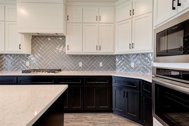 9321 NW 147th Ter, Yukon, OK 73099 - kitchen with appliances with stainless steel finishes, white cabinets, custom range hood, dark cabinetry, and backsplash