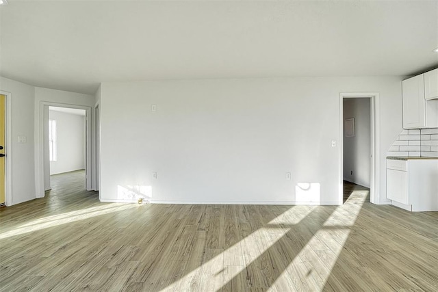 unfurnished living room with baseboards and light wood-style floors