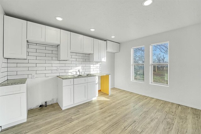 kitchen featuring a sink, tasteful backsplash, white cabinetry, recessed lighting, and light wood-style floors
