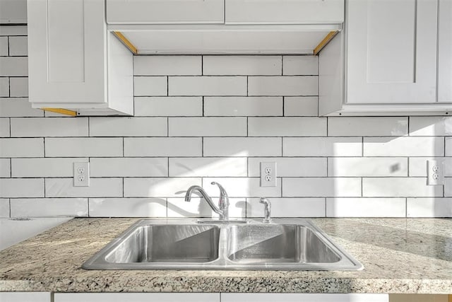 kitchen with white cabinetry, backsplash, and a sink