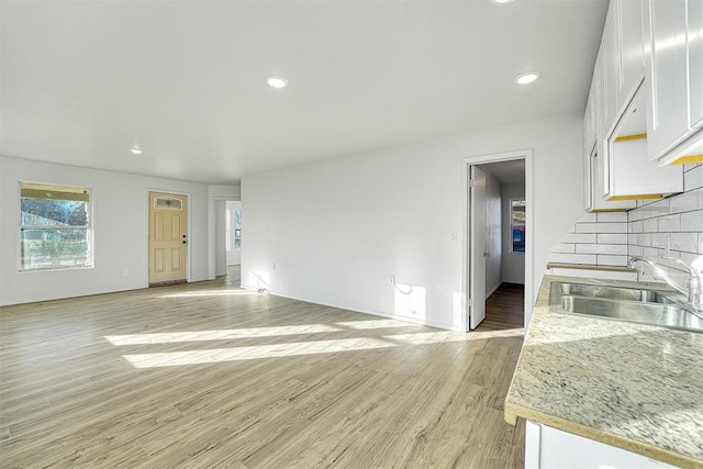 unfurnished living room featuring a sink, baseboards, light wood-style floors, and recessed lighting