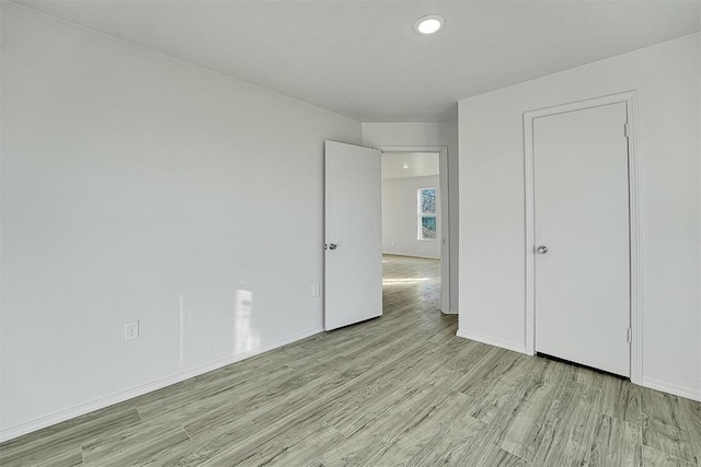 unfurnished bedroom with baseboards and light wood-type flooring