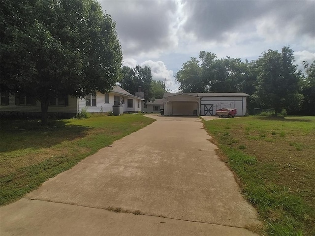 2005 E Cherokee Ave, Enid, OK 73701 - view of front of house featuring concrete driveway, a front yard, a carport, and an outbuilding