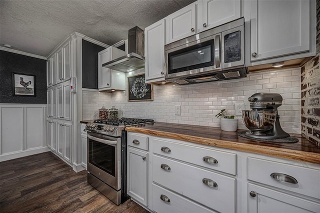 kitchen featuring wood counters, a textured ceiling, stainless steel appliances, wall chimney exhaust hood, and dark wood-style flooring