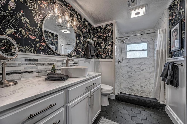 full bath with vanity, a textured ceiling, a shower stall, and toilet
