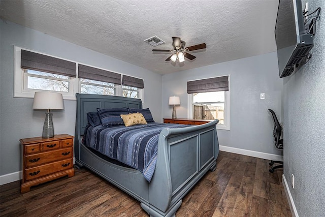 bedroom featuring visible vents, baseboards, a textured ceiling, a ceiling fan, and dark wood-style flooring