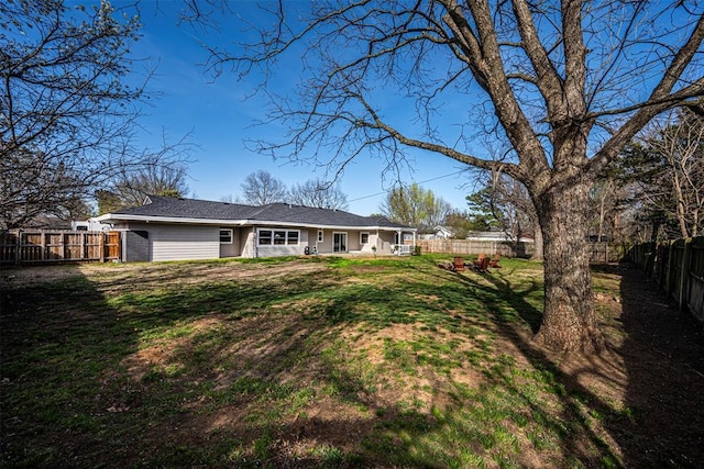 rear view of house with a lawn and a fenced backyard
